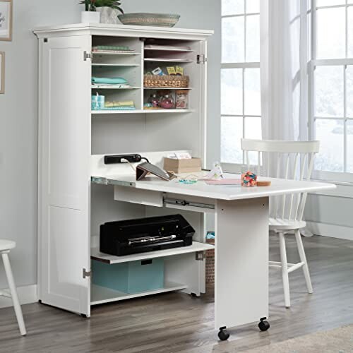 A white cabinet desk with office supplies and chair in a room.