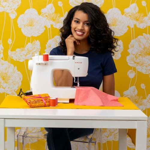 Smiling woman sitting at a sewing machine with fabric and thread